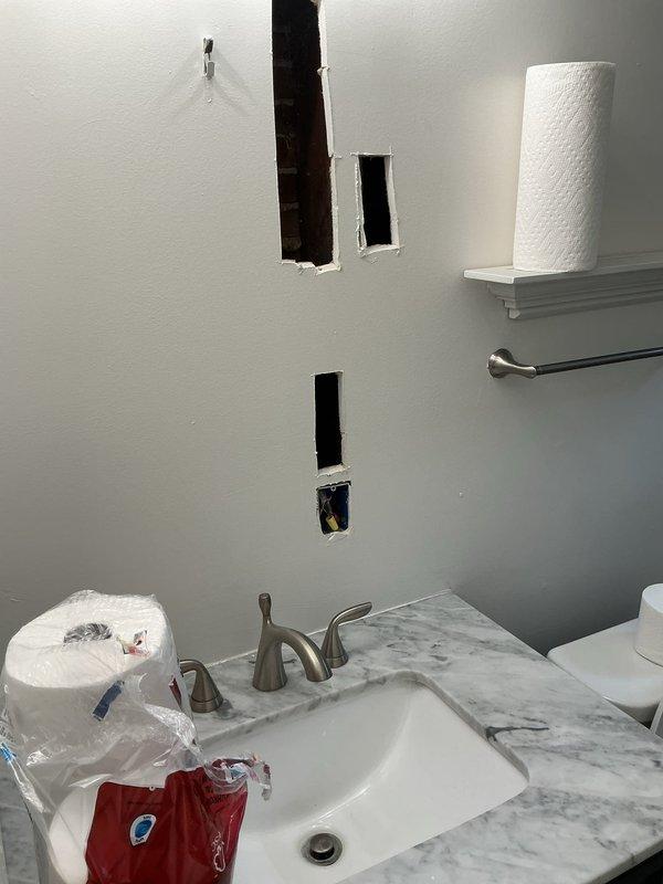 Completed electrical estimate and assessment for multiple fixture and outlet issues throughout the residence. Evaluated bathroom renovation requiring new outlet installation with visible wall openings prepared for electrical work. Inspected basement area with exposed hanging wires requiring proper termination and securing. Assessed non-functional outdoor lighting fixture and determined repair requirements. Examined garage space lacking electrical infrastructure for both outlet and lighting installation. Evaluated malfunctioning stairwell light fixture at upper landing. Identified four three-pronged outlets throughout the property that lack proper grounding and require remediation to meet current electrical code standards. Documented all conditions with photographic evidence showing bathroom wall penetrations with exposed wiring ready for fixture installation.