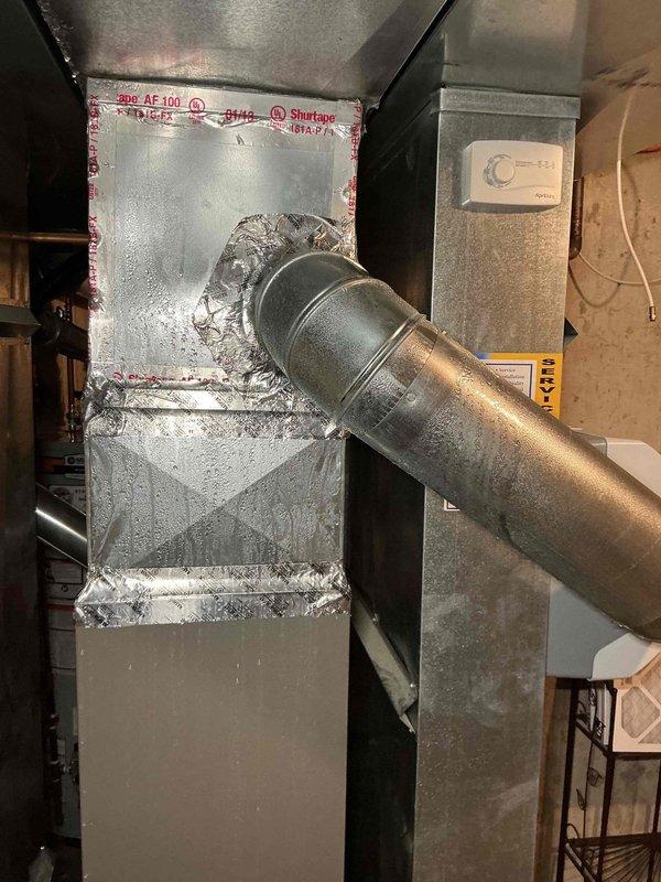 Responded to no cooling call with reported water leaking from furnace unit in basement. Upon arrival, found excessive condensation on air handler and ductwork due to inadequate insulation on cold surfaces in humid environment. The condensation had triggered the safety float switch, shutting down the cooling system as designed to prevent water damage. Verified drain line was clear and functioning properly. Inspected evaporator coil and confirmed normal operation with no refrigerant leaks. System had been operating in high humidity conditions causing moisture accumulation on uninsulated metal surfaces of plenum and supply ductwork. Recommended additional insulation be applied to all exposed cold air ductwork and plenum surfaces to prevent future condensation issues. Emptied safety pan, reset float switch, and restored system to normal cooling operation. Verified proper airflow and temperature split across evaporator coil. System operating as designed with adequate cooling capacity. Advis