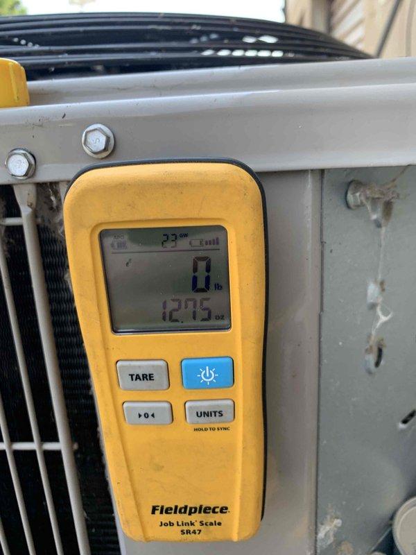 Responded to no cooling complaint on 1-year-old Bryant system located in attic. Upon arrival, contacted customer as requested and confirmed unit was powered off. Accessed attic-mounted equipment with ladder. Performed diagnostic evaluation using Fieldpiece digital manifold and refrigerant scale to assess system pressures, temperatures, and refrigerant charge. Testing revealed system was low on refrigerant, indicating a leak in the system. Documented readings and equipment conditions with photos showing measurement devices and condenser unit. Advised customer of findings and provided recommendations for leak detection service and refrigerant recharge to restore proper cooling operation.