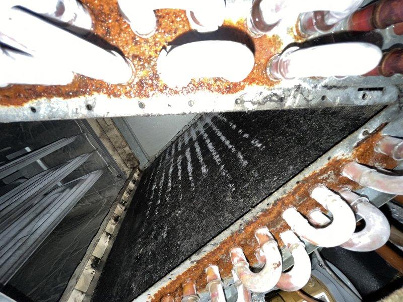 Responded to no cooling complaint on residential HVAC system over 10 years old. Upon inspection, found evaporator coil completely frozen with heavy ice buildup on refrigerant lines and coil surface, preventing proper airflow and heat exchange. Coil fins showed significant dust accumulation and debris restriction. Observed rust and corrosion on exterior metal components and framework indicating age-related deterioration. System was shut down per prior instruction to allow ice to thaw and prevent compressor damage from continued operation in frozen condition.