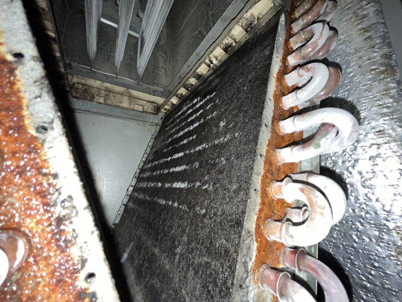 Responded to no cooling complaint on residential HVAC system over 10 years old. Upon inspection, found evaporator coil completely frozen with heavy ice buildup on refrigerant lines and coil surface, preventing proper airflow and heat exchange. Coil fins showed significant dust accumulation and debris restriction. Observed rust and corrosion on exterior metal components and framework indicating age-related deterioration. System was shut down per prior instruction to allow ice to thaw and prevent compressor damage from continued operation in frozen condition.