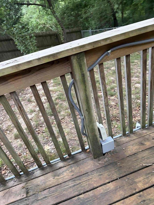 Installed new electrical circuit and outdoor lighting fixture on existing deck structure. Routed black electrical cable along deck railing system and mounted junction box to vertical post for proper connection and code compliance. Successfully completed wiring installation with all components secured and operational.