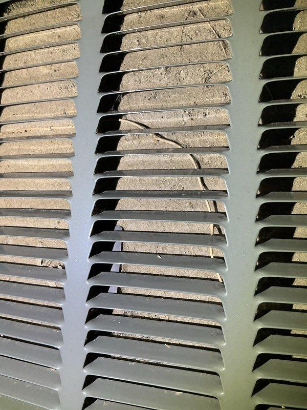 Responded to no cooling complaint with indoor temperature reading 80°F despite thermostat set to 72°F. Upon inspection, found 10+ year old outdoor condenser unit with severely restricted airflow due to heavy dust, dirt, and debris accumulation blocking louver fins and grilles. Performed thorough cleaning of condenser coils and ventilation louvers, removed plant debris and obstructions from unit exterior, and restored proper airflow to system. Unit tested successfully with normal cooling operation restored.