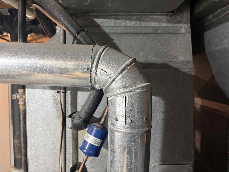 Responded to no-cool call for 11-year-old Rheem system with reported loud noises from outdoor unit. Upon arrival, contacted customer per request and performed diagnostic inspection of outdoor condenser unit to identify source of noise from either fan motor or compressor assembly. Inspected indoor air handler, ductwork connections, and refrigerant lines in basement mechanical area for related issues. Documented system condition with photos showing ductwork installation and basement HVAC infrastructure. Determined cause of operational concern and provided customer with findings and repair recommendations to restore proper system function.