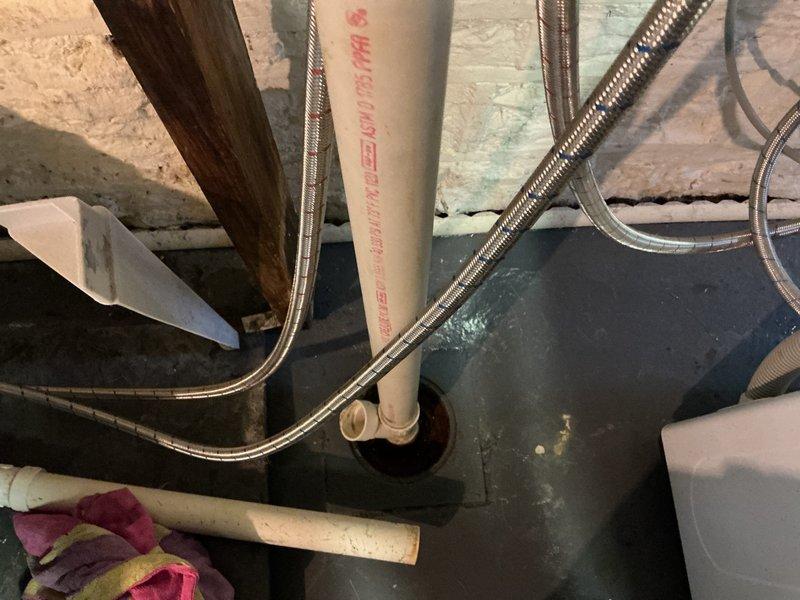Responded to follow-up service call for washing machine drain backing up and overflowing into basement floor drain. Previous technician was unable to clear blockage and suspected cracked floor drain trap. Attempted to clear obstruction using mechanical drain cleaning methods but was unsuccessful in opening the line. Upon inspection, confirmed that the floor drain trap assembly appears to be compromised and requires replacement rather than standard drain cleaning. Documented existing conditions with photographs showing floor drain configuration, surrounding PVC drainage piping, and water heater connections in utility area. Recommended scheduling replacement bid for new floor drain trap installation to resolve ongoing drainage issue.