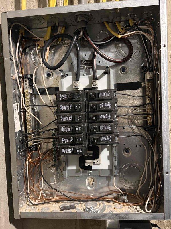 Completed comprehensive whole-home electrical inspection as part of Elite preventive maintenance agreement. Thoroughly examined main electrical panel, documenting breaker configuration, circuit labeling, wire connections, and overall system condition. Panel inspection revealed properly organized circuit breakers with handwritten identification labels, adequate wire management at service entry points, and functional bus bar connections. Photographed panel interior showing multiple circuit breakers, surge protection device, and color-coded wiring including black, white, yellow, brown, and copper conductors entering through conduits. Noted minor dust and debris accumulation at panel base requiring routine cleaning. All breakers appeared operational with visible amperage ratings. Panel enclosure showed good overall condition with no signs of rust, damage, or deterioration to mounting hardware or interior components.