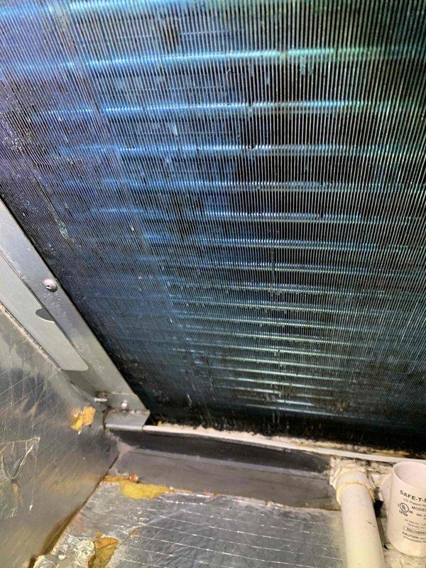 Responded to no-cool service call on 7-year-old Carrier split system at unit D. Upon inspection, found evaporator coil heavily soiled with accumulated dirt, debris, and microbial growth restricting airflow. Coil fins showed significant discoloration with dark staining throughout. Drain pan exhibited rust staining and degraded foam insulation at connection points, indicating prolonged moisture exposure and lack of routine maintenance. Cleaned evaporator coil assembly, cleared condensate drainage system, and restored proper airflow. System tested and returned to normal cooling operation.