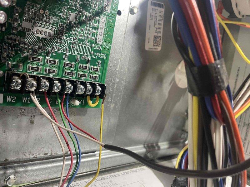 Responded to no cooling call with reported outdoor coil freezing condition on 10+ year old system located next to garage. Upon arrival, system had been off since 8:00 AM per homeowner. Performed diagnostic evaluation of control board and wiring connections, inspecting terminal connections and verifying proper wire placement at W2, W1, R, and G terminals. Documented control board condition and electrical connections with photos showing circuit board components, terminal block wiring, and bundled wire harnesses within control compartment. Advised on freeze-up causes and system status following initial assessment.