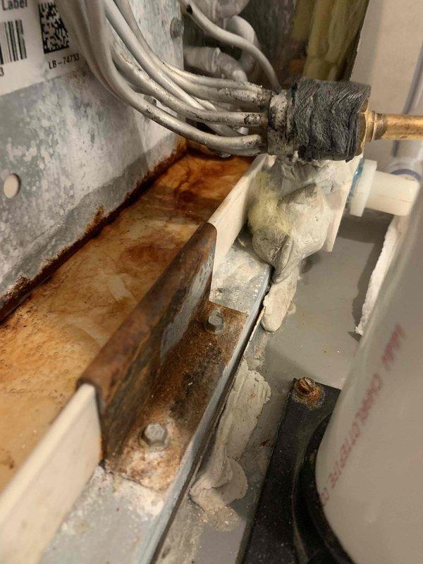 Responded to callback for second floor air conditioning unit experiencing water leakage one day after routine maintenance. Upon inspection, discovered the evaporator coil drain pan exhibited severe rust deterioration and corrosion throughout, with extensive mineral deposits indicating chronic moisture accumulation. The condensate drainage system showed signs of long-term failure, with rust staining concentrated along collection areas. Copper refrigerant lines and associated plumbing connections were inspected for integrity. Documented condition of corroded drain pan, deteriorated plumbing components, and compromised condensate management system. Unit identified as oldest system in building requiring drain pan replacement to resolve recurring leakage issue.