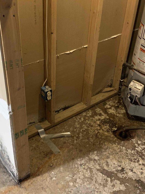 Performed camera location service in unfinished basement area to identify plumbing infrastructure within wall framing and concrete floor system. Documentation captured showing exposed wooden stud framing with foam insulation panels and utility connections, along with concrete floor surface conditions in renovation space requiring plumbing system assessment.