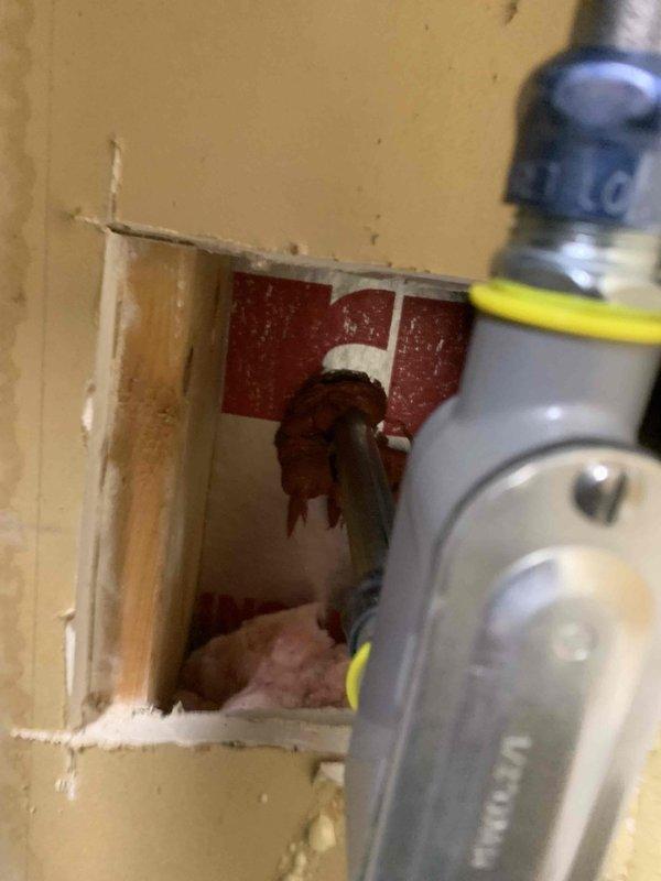 Completed electrical circuit installation and rewiring work involving wall penetration and disconnect box installation. Cut access opening in interior wall to route new wiring, exposing structural cavity for proper conductor placement. Installed and wired 160-amp electrical disconnect enclosure on exterior brick wall, terminating multiple branch circuits with appropriate black phase conductors and green grounding wire. All connections secured to terminal blocks with proper torque specifications. Flexible conduit installed for weather-resistant wire protection at entry point. Work performed in accordance with NEC requirements for residential electrical systems.