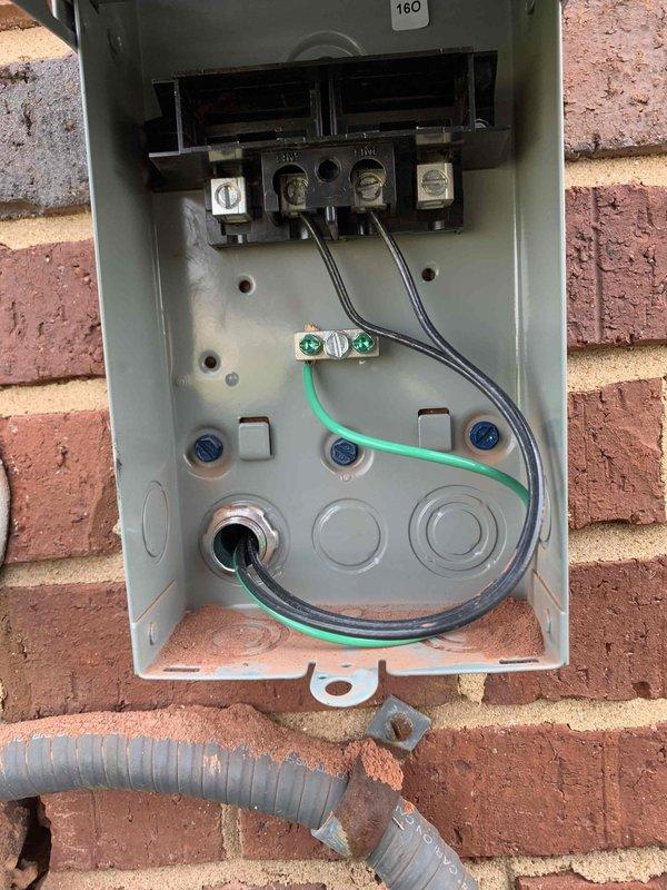 Completed electrical circuit installation and rewiring work involving wall penetration and disconnect box installation. Cut access opening in interior wall to route new wiring, exposing structural cavity for proper conductor placement. Installed and wired 160-amp electrical disconnect enclosure on exterior brick wall, terminating multiple branch circuits with appropriate black phase conductors and green grounding wire. All connections secured to terminal blocks with proper torque specifications. Flexible conduit installed for weather-resistant wire protection at entry point. Work performed in accordance with NEC requirements for residential electrical systems.