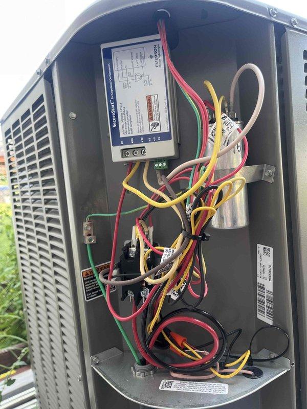 Installed soft start kit on residential outdoor HVAC unit to reduce startup current and improve compressor performance. Verified proper electrical connections, tested amperage draw at 26.7 amps using digital clamp meter, and confirmed all components functioning correctly after installation.