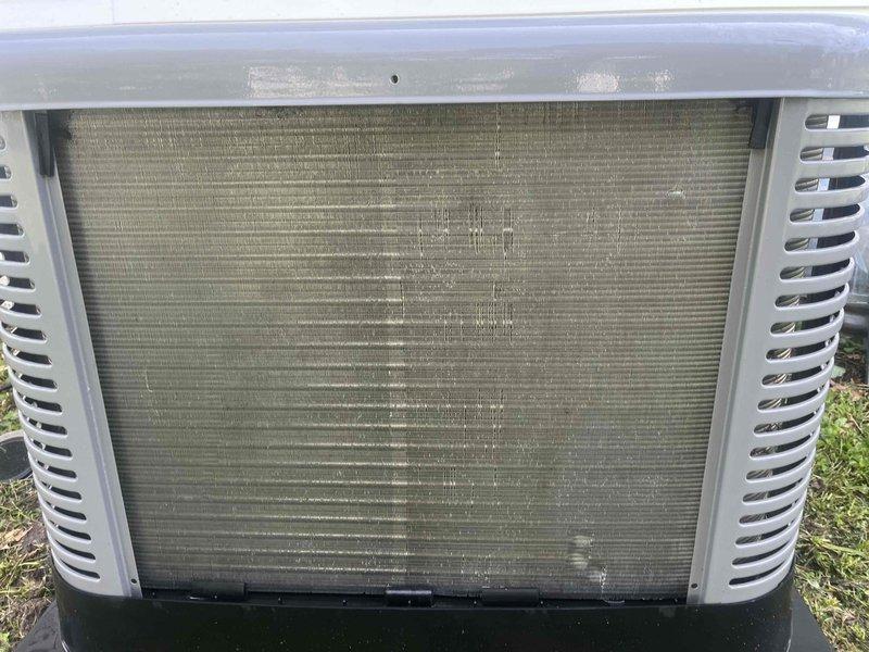 Responded to no cooling complaint with indoor temperature reaching 80 degrees on a 9-year-old air conditioning system. Upon arrival, performed visual inspection of outdoor condenser unit, noting significant dirt and debris accumulation on heat exchanger coil with visible streaking and staining across horizontal fins, which was restricting proper airflow and heat transfer. Inspected indoor evaporator coil assembly in attic space, checking refrigerant line connections, filter drier, condensate drain, and electrical components. Cleaned condenser coil to remove built-up contamination and restore adequate airflow through heat exchanger. Verified proper refrigerant line connections and system operation. System restored to normal cooling capacity following coil cleaning and inspection.