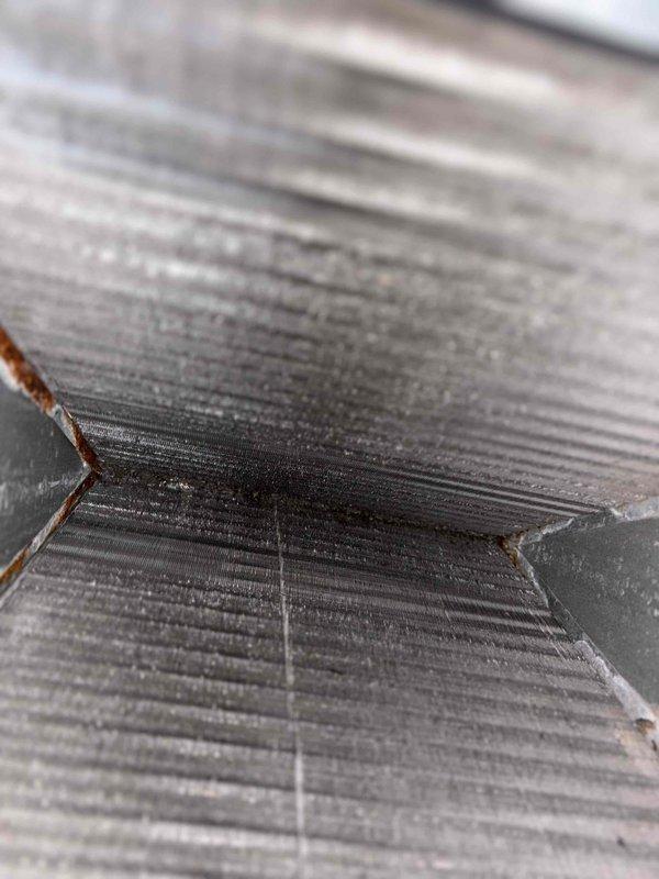Responded to no cooling complaint on residential air conditioning system. Upon inspection, discovered cracked heat exchanger with visible V-shaped fracture showing oxidation and material separation. Examined evaporator coil and found accumulated debris between aluminum fins affecting airflow efficiency. Documented equipment condition with photos showing heat exchanger damage and coil contamination. Verified furnace wet switch operation as requested. Replaced 24x28x1 air filter. System requires heat exchanger replacement due to safety concerns before further operation.