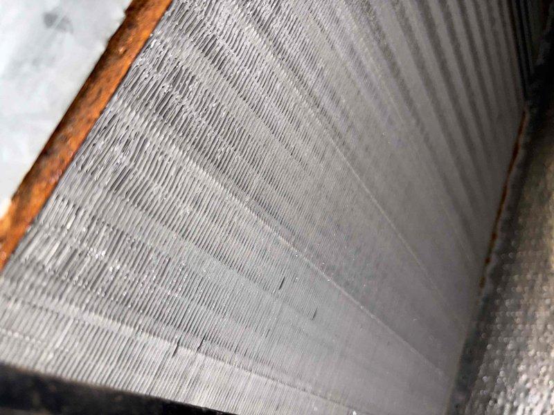 Responded to no cooling complaint on residential air conditioning system. Upon inspection, discovered cracked heat exchanger with visible V-shaped fracture showing oxidation and material separation. Examined evaporator coil and found accumulated debris between aluminum fins affecting airflow efficiency. Documented equipment condition with photos showing heat exchanger damage and coil contamination. Verified furnace wet switch operation as requested. Replaced 24x28x1 air filter. System requires heat exchanger replacement due to safety concerns before further operation.