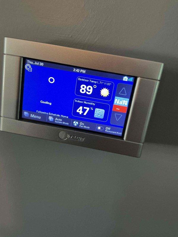 Responded to service call for thermostat displaying two dashes while system continued to cool properly. Upon inspection, found Trane digital thermostat experiencing communication error between display and HVAC system, though cooling operation remained functional. Verified thermostat functionality, cycled power to reset communication protocol, and confirmed proper temperature readings and system response restored with display showing correct indoor/outdoor temperatures and humidity levels.