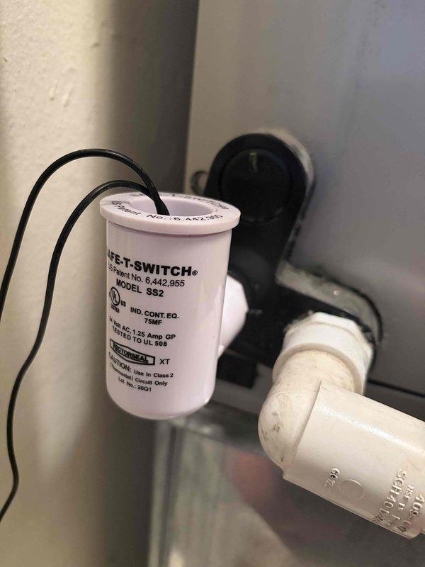Completed inspection of residential HVAC system located in utility closet apartment unit. Verified proper operation of air conditioning system including control module, electrical connections, and safety components. Documented existing equipment condition with photographs showing control box with multi-wire connections, finned heat exchanger coils, and mounted Safe-T-Switch SS2 condensate overflow safety device on drain line. All components confirmed operational and system functioning as designed.