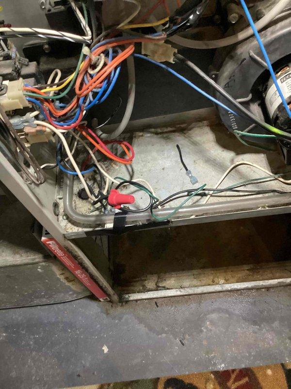 Responded to no-cool condition on 16-year-old residential air conditioning system with non-operational condenser fan motor. Upon arrival, performed comprehensive diagnostic evaluation of ground-level condenser unit and accessed internal components to assess blower motor, electrical connections, and refrigerant system integrity. Inspected wiring harness, capacitor, and motor windings; documented equipment condition with interior compartment showing accumulated debris in drain pan and exterior unit positioning in muddy soil conditions that may impact drainage and airflow efficiency.