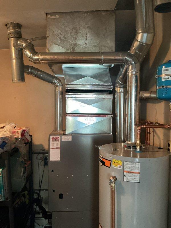 Installed a 50-gallon gas tall water heater in residential basement utility room. Connected copper supply lines, gas piping, and venting to existing infrastructure, with blue expansion tank mounted on wall for thermal expansion protection. Installation completed alongside existing HVAC furnace system with all connections properly secured and equipment operational.