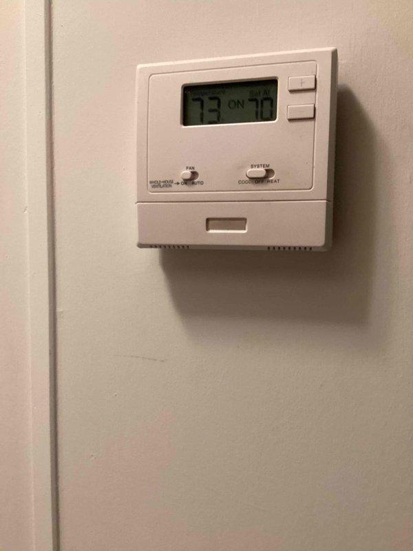 Responded to no cooling complaint on 10+ year old outdoor unit located at side of home. Upon arrival, found unit with significant exterior corrosion and deterioration consistent with age. Performed diagnostic evaluation of system components and thermostat operation, which was set to cooling mode with display reading 73°F. Verified fan operation per customer's pre-arrival instructions to leave fan running with AC off. Documented equipment condition showing extensive rust, paint degradation, and surface oxidation on compressor housing and associated hardware.