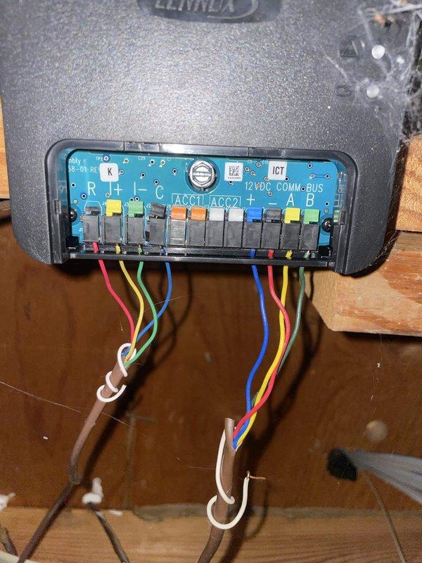 Responded to service call for thermostat malfunctioning with erratic behavior and temperature settings resetting randomly. Inspected Lennox system control board and wiring connections at hallway unit, verified all terminal connections on blue control module including 12VDC COMM/BUS terminals and R, A, B, and ACC1/ACC2 points. All wire connections were secure with proper voltage readings confirmed at +12V, A, B, and -12V terminals on the communication interface panel.