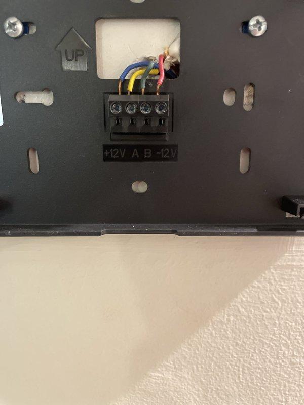 Responded to service call for thermostat malfunctioning with erratic behavior and temperature settings resetting randomly. Inspected Lennox system control board and wiring connections at hallway unit, verified all terminal connections on blue control module including 12VDC COMM/BUS terminals and R, A, B, and ACC1/ACC2 points. All wire connections were secure with proper voltage readings confirmed at +12V, A, B, and -12V terminals on the communication interface panel.