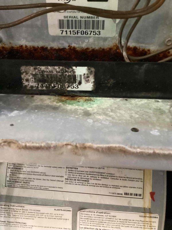 Responded to callback for water pooling around indoor air handler unit in basement. Upon inspection, found significant condensation on evaporator coil with water accumulation at base of unit. Identified excessive sweating on coil surfaces and surrounding components, with visible corrosion and rust staining on metal surfaces and copper refrigerant lines. Documented equipment condition showing advanced deterioration on cabinet panels, pipe connections, and mounting brackets. Investigation revealed drainage issue causing moisture buildup around air handler. Photographed serial number 7115F06753 and overall equipment condition for service records.