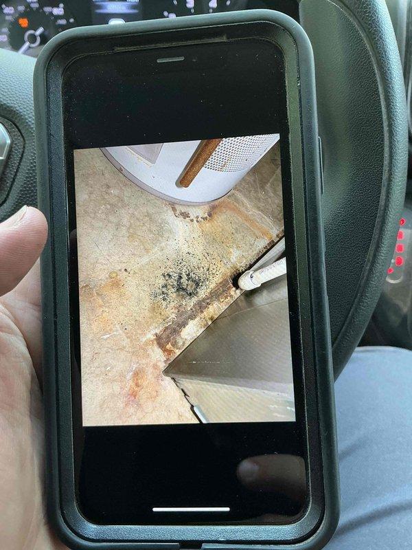 Responded to service call for rapidly soiling air filter on basement HVAC unit over 10 years old. Upon inspection, confirmed filter installed less than two weeks prior was completely blackened, indicating excessive dust contamination in the system or ductwork. Documented condition of both the contaminated filter and surrounding floor area showing significant dirt accumulation near the air handler and return vent. Identified potential issues with duct leakage or inadequate sealing allowing unfiltered air and debris to bypass filtration system. Recommended thorough duct inspection and cleaning to address source of excessive particulate matter entering the system.