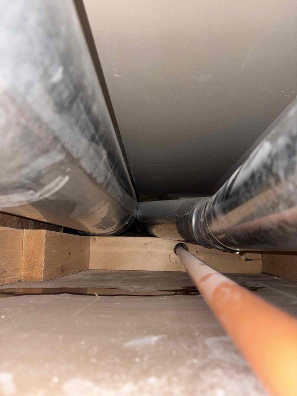 Responded to service call for suspected water leak from rooftop AC unit that was potentially misidentified as dryer leak during previous visit. Performed thorough inspection of six-year-old air conditioning system, including visual examination of condensate drain lines, drain pan, and ductwork accessible through attic space. Inspected flexible metal ductwork runs and surrounding ceiling areas for evidence of moisture intrusion or water damage. System operational check confirmed unit cooling properly with no immediate signs of active leakage at time of inspection. Documented conditions with photos of ductwork and accessible components in confined attic space for reference.
