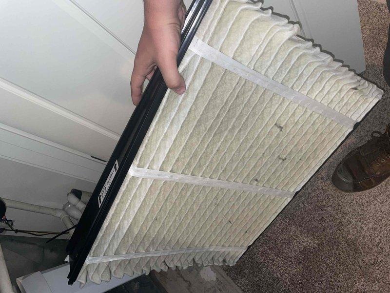 Completed comprehensive tune-up service on a 10-year-old residential air conditioning unit located on the side of the home. Performed standard maintenance inspection of the air handler cabinet, verifying electrical connections, circuit breaker operation, and proper wiring configuration throughout the system. Inspected and documented a moderately soiled air filter showing significant dirt accumulation in the lower pleated sections, indicating normal system operation and particle capture over the service period.