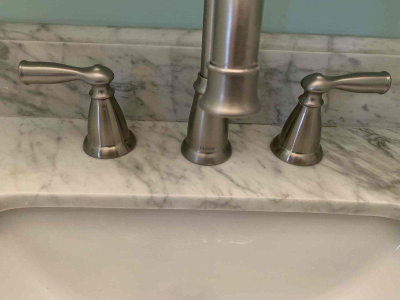 Responded to dual bathroom sink clog in 1960s-era home where both fixtures were connected to shared drainage system. Assessed widespread faucet configuration with brushed nickel finish on marble countertop and undermount porcelain basins. Cleared obstruction from common drain line serving both sinks, restoring proper drainage and flow to both fixtures. Tested both basins for complete water evacuation and verified no backup between connected sinks.