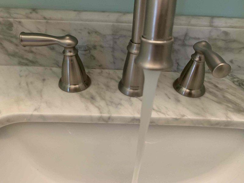 Responded to dual bathroom sink clog in 1960s-era home where both fixtures were connected to shared drainage system. Assessed widespread faucet configuration with brushed nickel finish on marble countertop and undermount porcelain basins. Cleared obstruction from common drain line serving both sinks, restoring proper drainage and flow to both fixtures. Tested both basins for complete water evacuation and verified no backup between connected sinks.