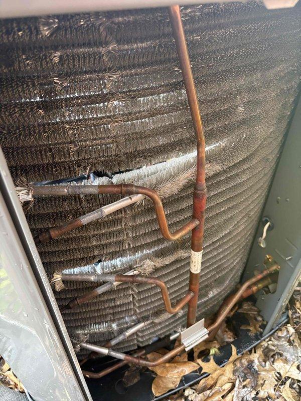 Completed comprehensive cooling system tune-up on single outdoor AC unit. Inspected and replaced heavily soiled air filter showing significant particulate accumulation. Condenser coils exhibited substantial debris buildup with clogged fins and organic matter collected at base; cleaned coils to restore proper airflow and heat transfer efficiency. Inspected refrigerant lines and connections for proper insulation and secure fittings. System returned to optimal operating condition.