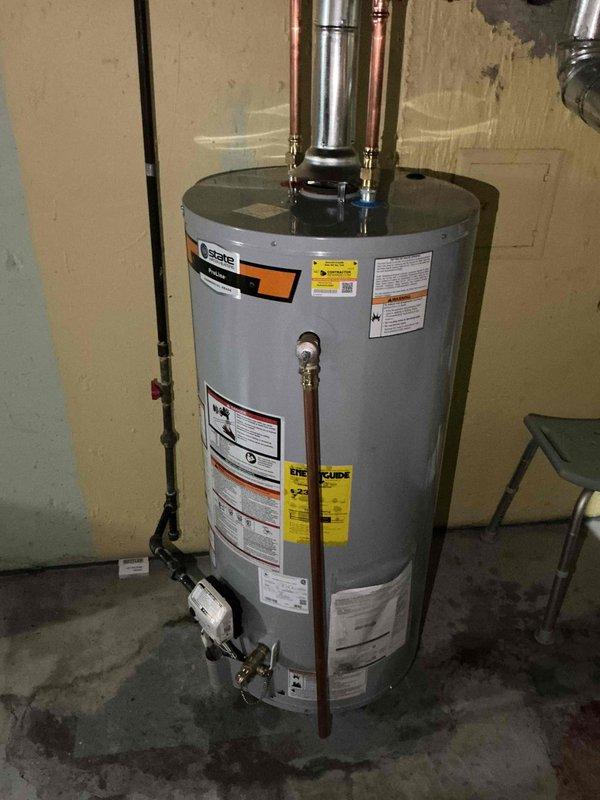 Installed 40-gallon short gas water heater in basement utility area. Connected hot and cold water supply lines with copper piping, installed pressure relief valve, and attached stainless steel flue venting to exhaust system. Applied required plumbing identification sticker and ensured all connections met code requirements under permit 26PLU-15924. Unit tested and operational upon completion.