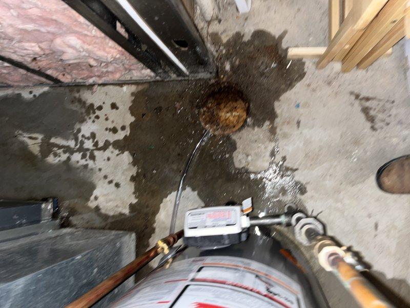 Responded to no-cooling call and found water leaking from bottom of furnace unit. Upon arrival, discovered significant water damage on concrete floor surrounding equipment, with extensive staining and moisture saturation indicating ongoing leak. Inspected HVAC system and identified heavily contaminated air filter with substantial dirt and particulate buildup affecting approximately one-third of filter surface. Advised customer that unit had been properly shut off per instructions to prevent further water damage. Documented conditions with photographs showing water heater installation area, floor damage patterns, and compromised filter condition. Recommended immediate repair of leak source and filter replacement to restore proper system operation.