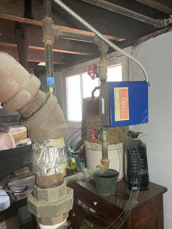 Responded to service call for reported boiler leak in basement mechanical room. Upon inspection of aging boiler system (10+ years), identified active leak at copper piping connection joint near circulator assembly. Leak originated from deteriorated union fitting showing visible corrosion and mineral deposits. Tightened connection and assessed surrounding piping infrastructure, noting aged insulation wrapping on distribution lines and general wear consistent with system age. Documented existing conditions including corroded fittings, expansion tank connections, and overall system configuration with photographic evidence for customer records. System tested and verified operational with no active leaking at time of departure.