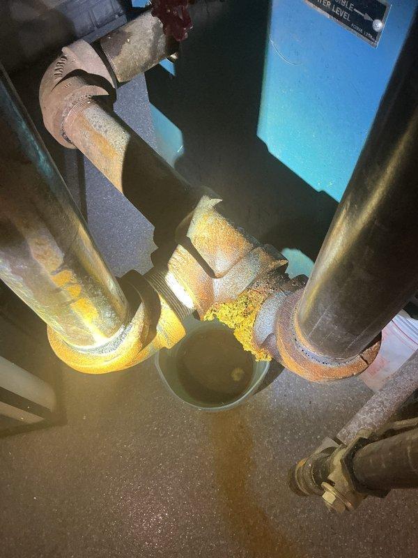 Responded to service call for reported boiler leak in basement mechanical room. Upon inspection of aging boiler system (10+ years), identified active leak at copper piping connection joint near circulator assembly. Leak originated from deteriorated union fitting showing visible corrosion and mineral deposits. Tightened connection and assessed surrounding piping infrastructure, noting aged insulation wrapping on distribution lines and general wear consistent with system age. Documented existing conditions including corroded fittings, expansion tank connections, and overall system configuration with photographic evidence for customer records. System tested and verified operational with no active leaking at time of departure.