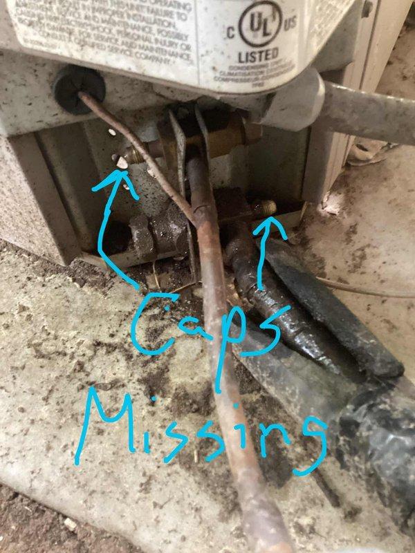 Performed complimentary second opinion inspection on air conditioning system to evaluate reported refrigerant leak. Upon examination of the refrigerant line connections, identified missing service port caps on multiple Schrader valve fittings, which can allow refrigerant loss and contamination entry into the system. Documented conditions with photos showing corroded copper tubing, aging valve assemblies, and exposed service ports requiring proper sealing to maintain system integrity.