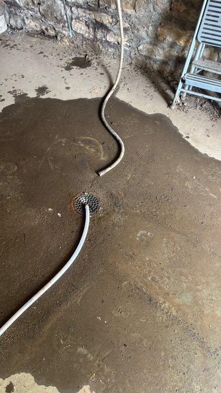 Responded to basement floor drain clog as reported. Upon arrival, located the affected floor drain in the basement area and assessed the blockage. Utilized drain cleaning equipment with cutting attachment as specified to clear the obstruction from the floor drain line. Successfully restored proper drainage flow and verified system operation. Documented conditions with photos showing the exterior drainage grate and basement floor drain area with visible moisture present prior to service completion.