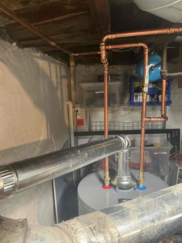 Completed installation of 40-gallon short gas water heater in basement utility area. Installed new copper supply piping with hot and cold shut-off valves, 3/4" pressure reducing valve, and blue thermal expansion tank mounted to ceiling joists. All connections properly soldered and secured per code requirements. Plumbing permit #26PLU-16101 obtained and ID sticker applied to installation. System tested for proper operation and checked for leaks. Unit staged and ready for customer use.
