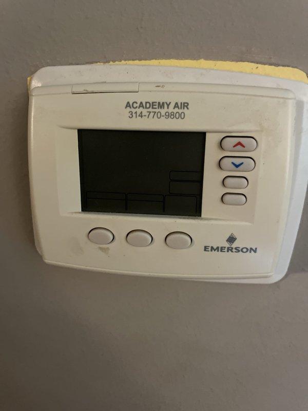 Responded to service call for non-functional thermostat in upstairs hallway. Upon arrival, found existing Emerson thermostat with inoperative display and unresponsive buttons, showing signs of age and wear with discoloration. Replaced failed unit with new White-Rodgers programmable thermostat. Verified proper system operation with cooling mode activated, display functioning correctly showing room temperature of 92 degrees and setpoint of 72 degrees. System tested and confirmed operational.