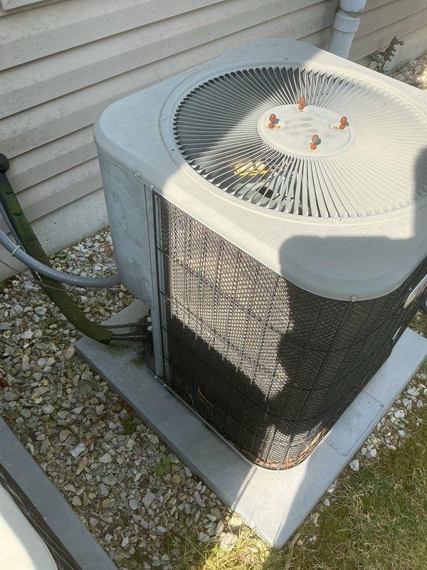 Responded to a no-cooling complaint on a Lennox HVAC system with inadequate temperature differential and abnormal humming noise from the outdoor condenser unit. Upon inspection, found the outdoor unit's condenser coil heavily soiled with dirt and debris accumulation, particularly on the lower sections of the mesh grille, which was restricting airflow and reducing system efficiency. The indoor air handler showed signs of requiring maintenance service. Performed thorough cleaning of the condenser coil to restore proper airflow through the heat exchanger. Addressed the humming noise issue at the outdoor unit and verified proper fan operation. Following service, tested system performance and confirmed cooling differential returned to acceptable range between 16-22 degrees. System restored to normal operating condition with improved airflow and proper refrigerant heat exchange.