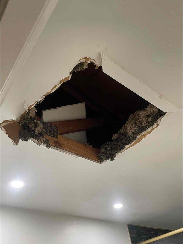 Responded to water leak complaint affecting lower level unit from upper HVAC system. Upon investigation, accessed attic space and located source of water intrusion traveling down condensate drain line from upper air handler. Created ceiling access point to inspect drain routing and confirmed blockage causing overflow condition. Cleared obstruction from primary drain line, verified proper drainage flow, and tested system operation to ensure leak was resolved. Documented attic ductwork configuration and drain line pathway for service records.