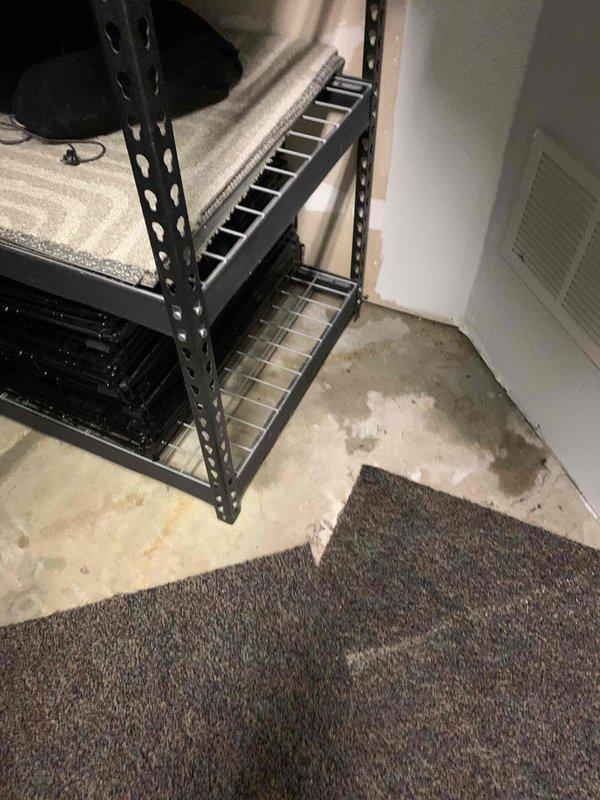 Responded to service callback regarding water leakage from condensate basin on ground-level outdoor unit. Upon inspection, discovered condensate drain hose had been left disconnected during previous service visit, resulting in water overflow onto basement concrete floor and adjacent carpeting. Reconnected condensate drain hose to proper discharge point and verified secure connection. Tested system operation and confirmed condensate now draining properly with no further leakage from basin. Documented water damage to concrete floor and carpet edge with photos for customer records.