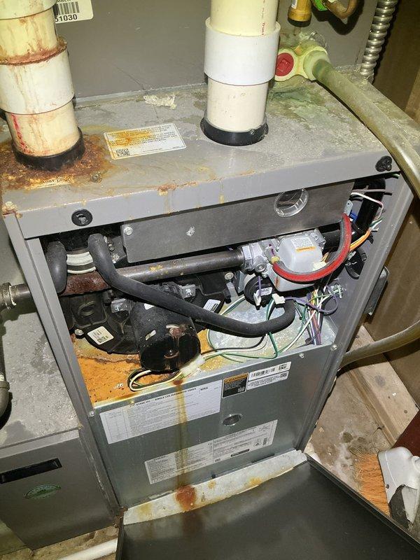 # HD#F61374543

Responded to service call for 10-year-old air conditioning system not cooling. Upon arrival, performed visual inspection of outdoor condensing unit and indoor furnace components. Documented current system condition with photos showing outdoor unit location and indoor HVAC equipment with access panel removed for inspection.

Observed outdoor condensing unit positioned on concrete pad with visible weathering and debris accumulation on surrounding surface. Indoor inspection revealed furnace unit with standard gas piping, electrical wiring, and blower assembly. Noted rust staining present around PVC condensate drain pipe connections at top of furnace unit, indicating potential moisture exposure over time. Unit specifications and manufacturer labels documented for reference.

Verified best contact number on file for follow-up communication. System assessed and findings documented for further diagnostic evaluation or recommended service actions.