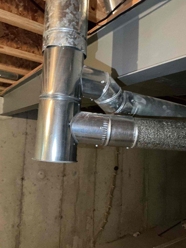 Completed flue pipe repair in basement mechanical space by installing new 5x4x4 tee fitting and 2 feet of 4-inch flue pipe. Replaced damaged sections of galvanized ductwork connections with properly sealed joints and metal strapping to ensure code-compliant venting. System tested and confirmed operational with proper draft and ventilation restored.