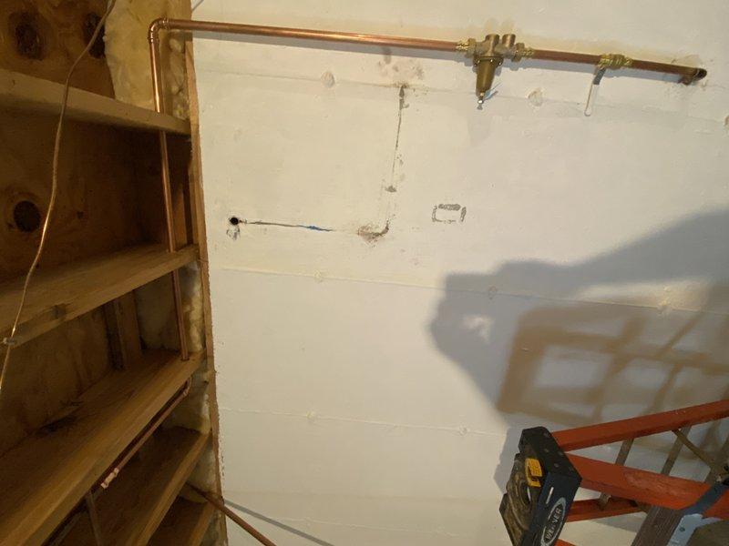 Completed comprehensive plumbing rough-in installation for basement bathroom renovation under permit. Relocated main water line pressure reducing valve and main shut-off valve from horizontal rafter installation to vertical riser configuration within 4" of wall, requiring removal of existing 3/4" flare x FIP connections, unsweating horizontal main, and installing new 3/4" copper 90-degree fitting with ball valve and PRV. Drilled three rafter penetrations for proper main line routing. Replaced front hose bibb and associated basement shut-off valve with new fixtures.

Installed new sump pump system with check valve and rerouted 1" discharge line, securing properly to wall structure for code compliance. Added two 3/4" tee fittings with ball valves on supply lines to service new basement bathroom fixtures. Performed complete shower drain reconfiguration by removing existing first-floor shower drain piping from base to tee connection, then repipe in 2" diameter with routing above rafter lin