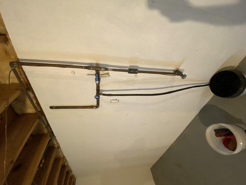 Completed comprehensive plumbing rough-in installation for basement bathroom renovation under permit. Relocated main water line pressure reducing valve and main shut-off valve from horizontal rafter installation to vertical riser configuration within 4" of wall, requiring removal of existing 3/4" flare x FIP connections, unsweating horizontal main, and installing new 3/4" copper 90-degree fitting with ball valve and PRV. Drilled three rafter penetrations for proper main line routing. Replaced front hose bibb and associated basement shut-off valve with new fixtures.

Installed new sump pump system with check valve and rerouted 1" discharge line, securing properly to wall structure for code compliance. Added two 3/4" tee fittings with ball valves on supply lines to service new basement bathroom fixtures. Performed complete shower drain reconfiguration by removing existing first-floor shower drain piping from base to tee connection, then repipe in 2" diameter with routing above rafter lin