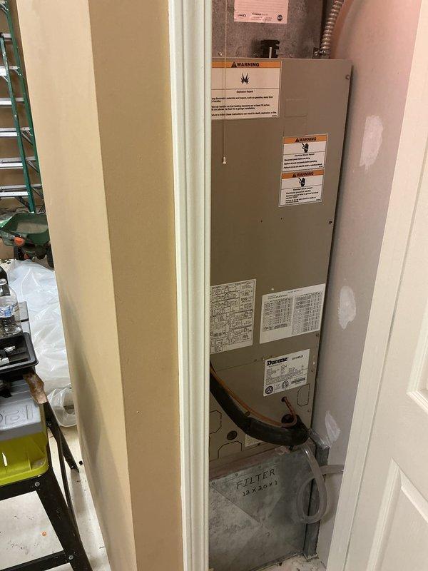 Responded to no cooling complaint for basement air conditioning system. Upon arrival, found 21-year-old outdoor unit that had been shut off per prior instructions. Inspected beige air handler unit in utility area and verified electrical panel connections, breaker positions, and condensate drain system. Documented equipment conditions with photos showing air handler installation, warning labels, drain pan, and electrical panel with associated wiring and circuit breakers for service records.